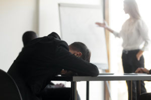 a guy asleep at his desk in an office meeting