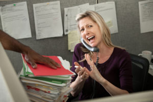harried woman on her phone in her office at her desk
