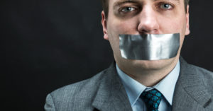 Man in suit with silver tape over his mouth